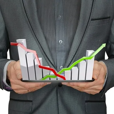 A businessman holding a tablet displaying a graph and bar chart