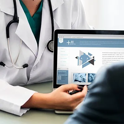 A doctor reviewing patient information on a laptop screen during a telemedicine consultation.
