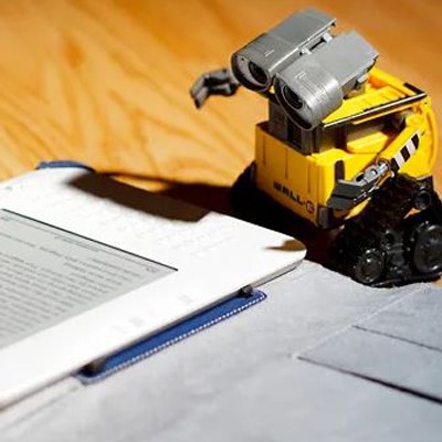 A toy robot and a Kindle device placed side by side.