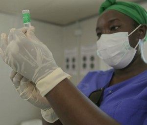 a woman in a surgical mask and gloves holding a tube