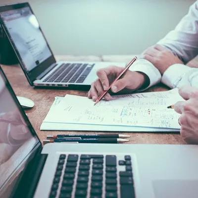 Two coworkers focusing on laptop and paperwork